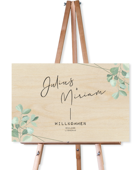 Willkommensschild aus Holz mit kursiver Schrift und Blättern